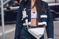 Street style, woman wearing Prada outfit: pale pink cropped top from Prada, white leather cross body bag, navy blue denim jacket Royalty Free Stock Photo