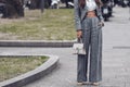 Street style, woman wearing white cropped shirt, a gray blazer jacket, gray matching suit pants, a beige leather handbag and