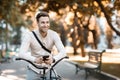 Street style. Young stylish man texting on phone while sitting on bike