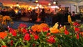 Street  summer night city life yellow orange flowers on front cafe where people relaxing under tent blurred street lamp light in T Royalty Free Stock Photo