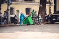 Street sweeper with a salakot hat carrying the garbage bin and a broom in Vietnam, Hanoi City