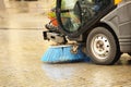 A street sweeper sweeps up a stone pavement with a strong brush in rainy weather. Maintaining clean tourist city. Preventing