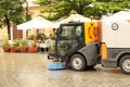 A street sweeper sweeps up a stone pavement with a strong brush in rainy weather. Maintaining clean tourist city. Preventing