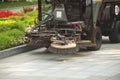 A street sweeper sweeps up a stone pavement with a strong brush in rainy weather. Maintaining clean tourist city. Preventing