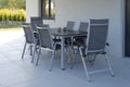 On the street terrace there are a gray table and six chairs made of metal and fabric, mounted on a tile. Beautiful modern romantic