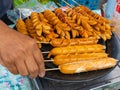 A Street Vendor Hand is Picking a Bamboo Sausage Skewer