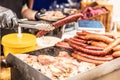Street vendor holds large sausage by pliers during a sale at the street food fair Royalty Free Stock Photo