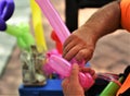 A street vendor is making balloon figures trying to make a living by counting on tips