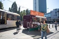 Street vendor sells ice cream in busy city centre square with people and tram