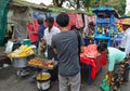 Street vendors selling sweet corn, cut red watermelon and vegetarian fritter to customers