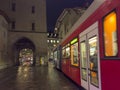 Street view of Bern. Blue red tram goes on the street near walking people in the night time.