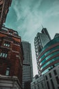 Street view looking up into the massive skyscrapers of london city, several tall buildings illuminated by teal sunlight.Old orange Royalty Free Stock Photo