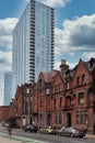 Street view of an old, red brick apartment building with modern office skyscraper behind Royalty Free Stock Photo