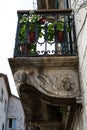 Street view of a pretty stone house facade with a small balcony with a wrought iron railing and potted plants. Kotor, Montenegro