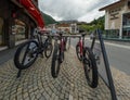 Street view with a rack filled with rental bikes during summer. Rack is posted at the side of the street. Daytime. Rental bikes