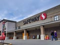 Street view of a Safeway grocery store with people approaching the entrance to shop for food