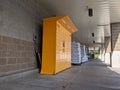 Street view of a set of bright yellow Amazon parcel lockers outside of a grocery store