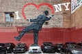 A street wall painting showing a gentleman that draws the heart of I Love NY