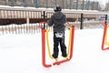 Street workout equipment in winter, outdoor sport fitness and bodybuilding. Boy in a sport playground doing workout exercises Royalty Free Stock Photo