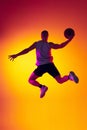 Streetballer. Male basketball player, athlete jumping with ball isolated on gradient yellow orange background in neon