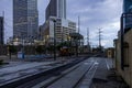 a streetcar riding along the tracks on the street with hotels, skyscrapers and office buildings in the city skyline