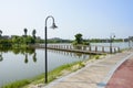 Streetlamps by lakeside path before footbridge in sunny summer m