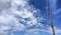 Streetlight and utility pole set against a vivid blue sky filled with dramatic white clouds Royalty Free Stock Photo