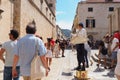 On the streets of Dubrovnik Croatia, happy vacationers walk and buy souvenirs from the seller in the national festive