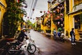 Streets of Hoian ancient town after rain shower with man on a motorbike and traditional lantern lamps above. Hoi An, Vietnam - 28