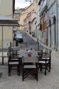 Streets of Lisbon. Table and chairs. AlcÃÂ¢ntara. Portugal. Red building. Windows. Door. Blue and violet. Authentic Portugal.