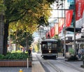 A streetscape of Christchurch with tramway, trees and red banners