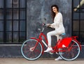 Streetstyle. Beautiful brunette girl in trendy, white outfit posing with a trendy vintage red bicycle outdoors. Royalty Free Stock Photo