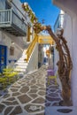 Streetview of Mykonos town with yellow chairs and tables and stairs, Greece