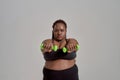 Strength and Experience. Plump, plus size african american woman in sportswear reaching arms forward, holding green