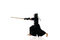Strength. Man, professional kendo athlete in black uniform with sword, shinai training against white studio background. Royalty Free Stock Photo