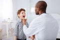 Little boy opening mouth for male doctor