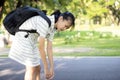 Stress asian child girl carrying heavy school bag or backpack, female teenage feeling pain on back, full of books on her back,