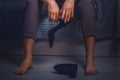 Stress and fatigue at work. A woman in a suit , sitting on the bed and holding a Shoe in her hand. Bare feet close-up Royalty Free Stock Photo