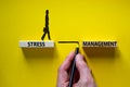 Stress management symbol. Wooden blocks with words `Stress management`. Yellow background. Businessman hand, businesswoman icon.