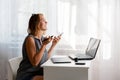 Stress at work. A young Caucasian woman screams in exasperation, holding a phone in her hands. There is a light window in the Royalty Free Stock Photo