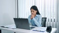 Stress young asian woman is thinking about her work and is looking at the laptop computer at the office Royalty Free Stock Photo