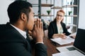 Stressed African-American businessman listening female team leader taking part at business meeting in conference room.