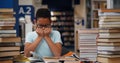 Stressed African-American teen student crying sitting at table with stack of books in library Royalty Free Stock Photo