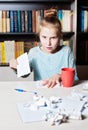 Girl angry at the table, in hands crumpling a piece of paper