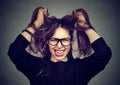 Stressed angry woman pulling hair out screaming on gray wall background Royalty Free Stock Photo