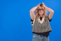 Stressed and anxious caucasian young woman with her arms up. Angry look. Blue background studio shot. Royalty Free Stock Photo