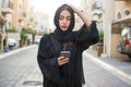 Stressed Arab woman with hand on head reading something on her mobile phone outdoors Royalty Free Stock Photo