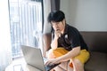 Stressed asian businessman sitting on a sofa at home and working on a laptop. Royalty Free Stock Photo