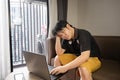 Stressed asian businessman sitting on a sofa at home and working on a laptop. Royalty Free Stock Photo