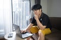 Stressed asian businessman sitting on a sofa at home and working on a laptop. Royalty Free Stock Photo